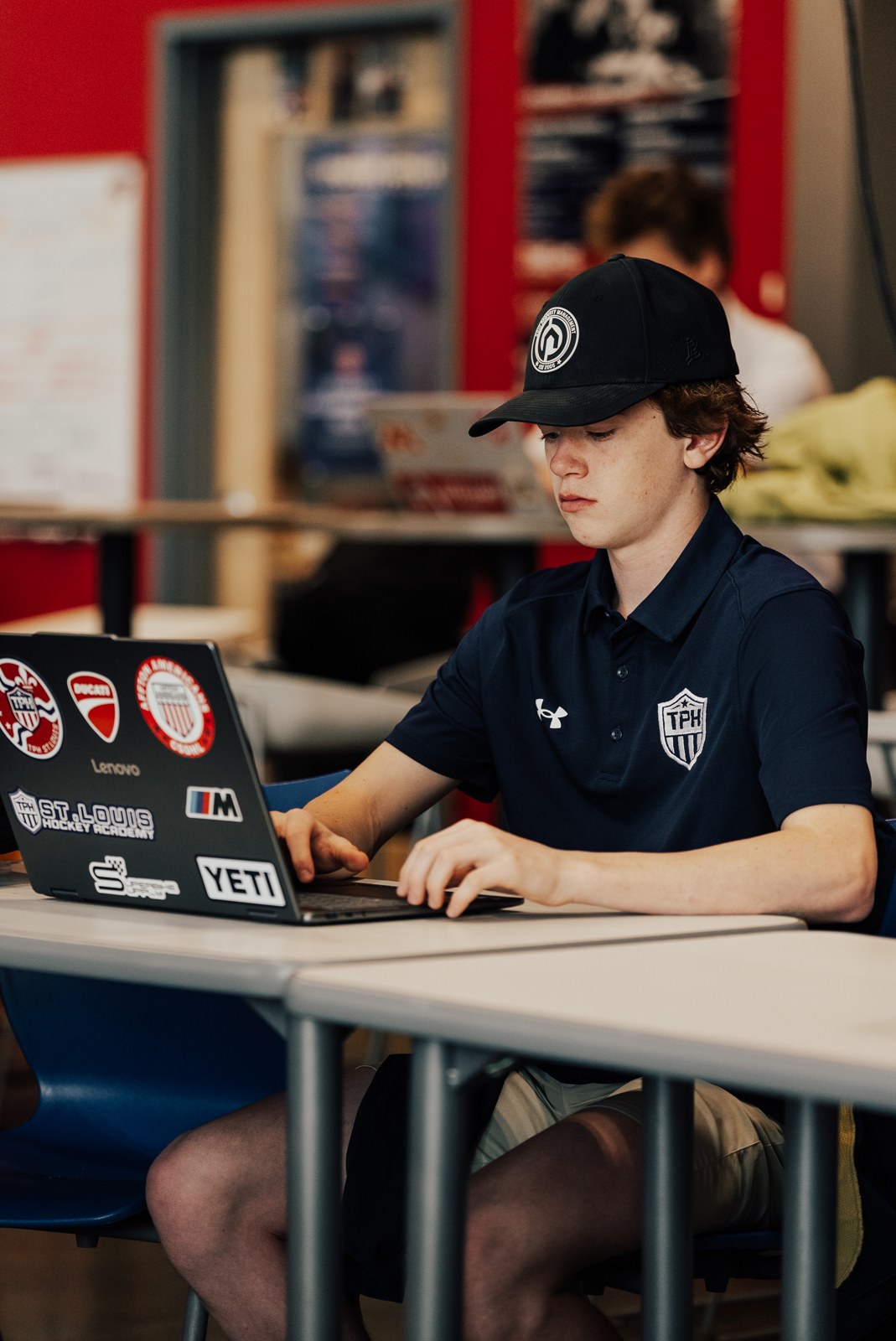 Student in a TPH St. Louis cap working on his laptop