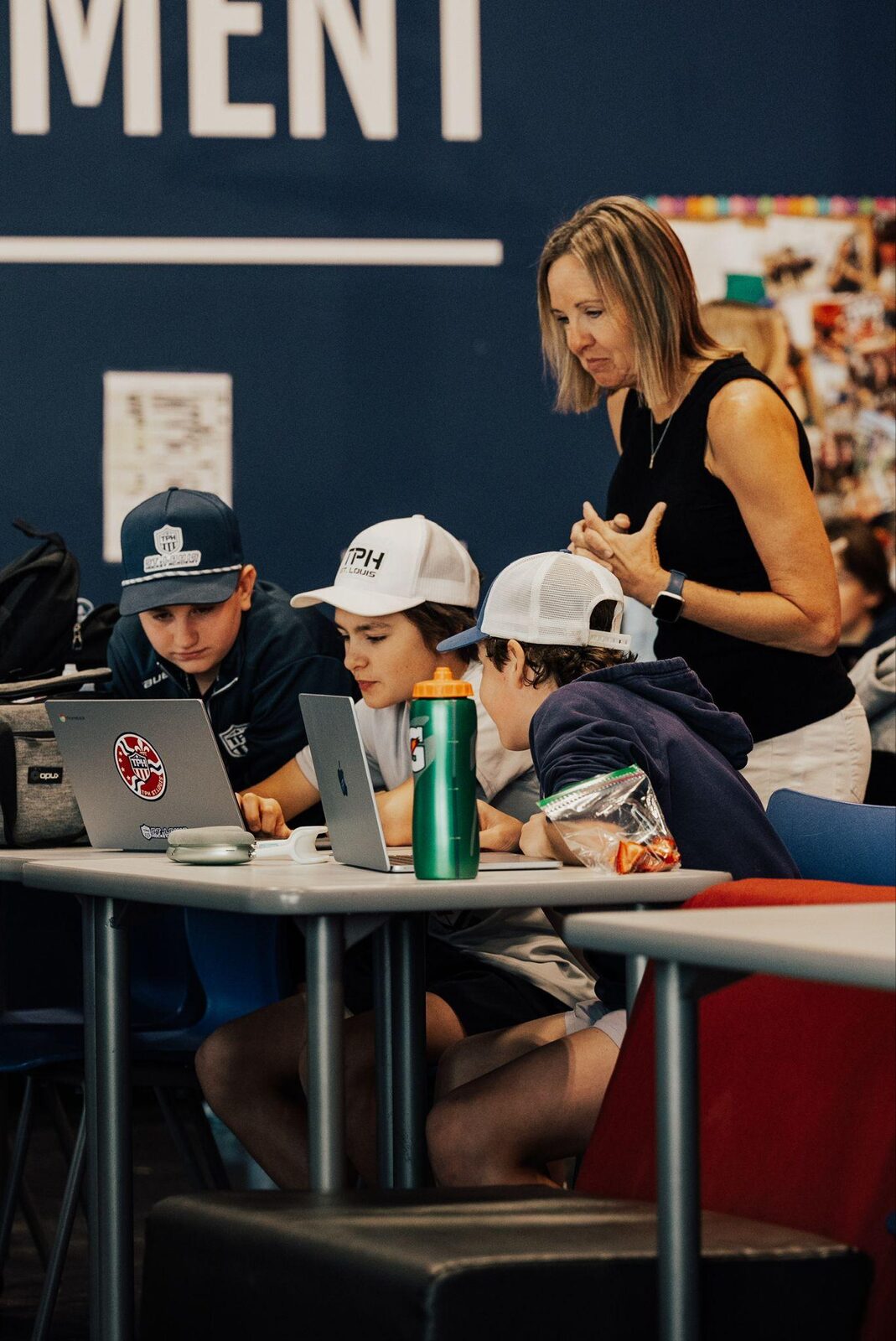 Staff mentoring young students at their laptops